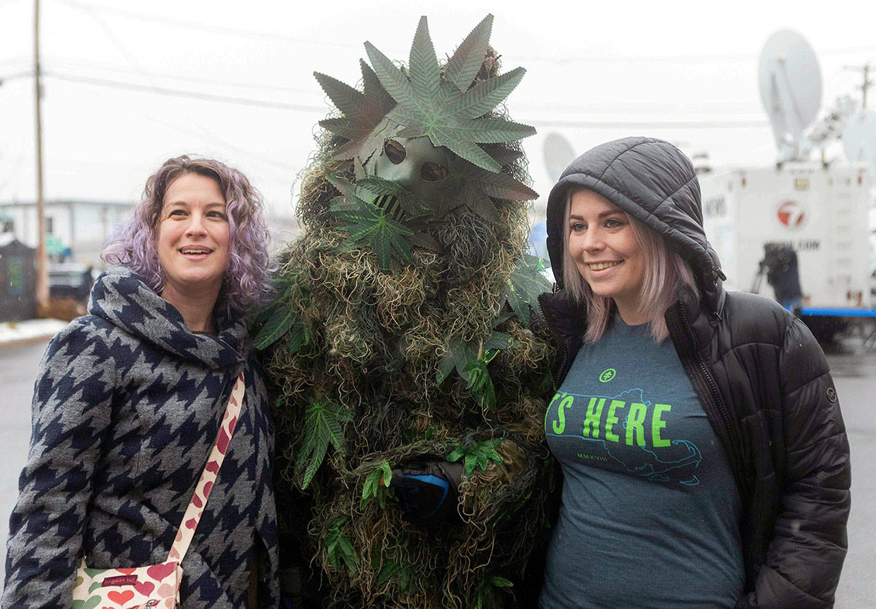 A man wearing a costume of “Potsquatch” poses with customers outside New England Treatment Access cannabis dispensary on the first day of legal recreational marijuana sales Tuesday in Northampton, Massachusetts. (Leon Nguyen/The Republican via AP)