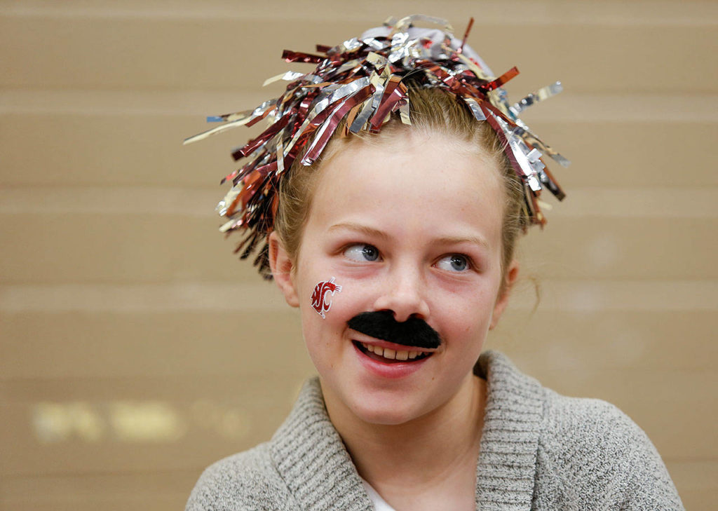 Emma Rice’s mustache shows her support for the Cougars as Dutch Hill Elementary held an Apple Cup-themed Dads ‘n Donuts event, with the gym decked out in Cougar and Husky colors, on Nov. 21, 2018, in Snohomish. (Andy Bronson / The Herald)
