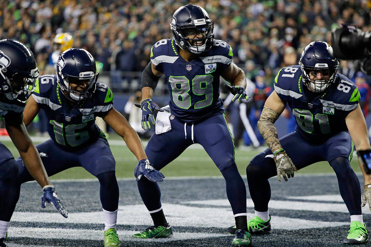 Seahawks wide receiver Doug Baldwin (89) takes part in a touchdown celebration with Tyler Lockett (left) and Nick Vannett (right) after Baldwin caught a pass for a touchdown during the first half of a game against the Packers on Nov. 15, 2018, in Seattle. (AP Photo/Elaine Thompson)
