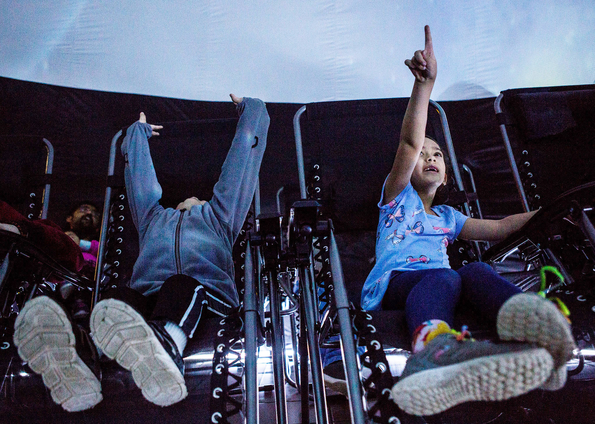 Eddy Neal, 3, left, and sister Lily Neal, 5, right, look up at the projection on the inside of the Planetarium 360 at the Everett Mall on Saturday. (Olivia Vanni / The Herald)