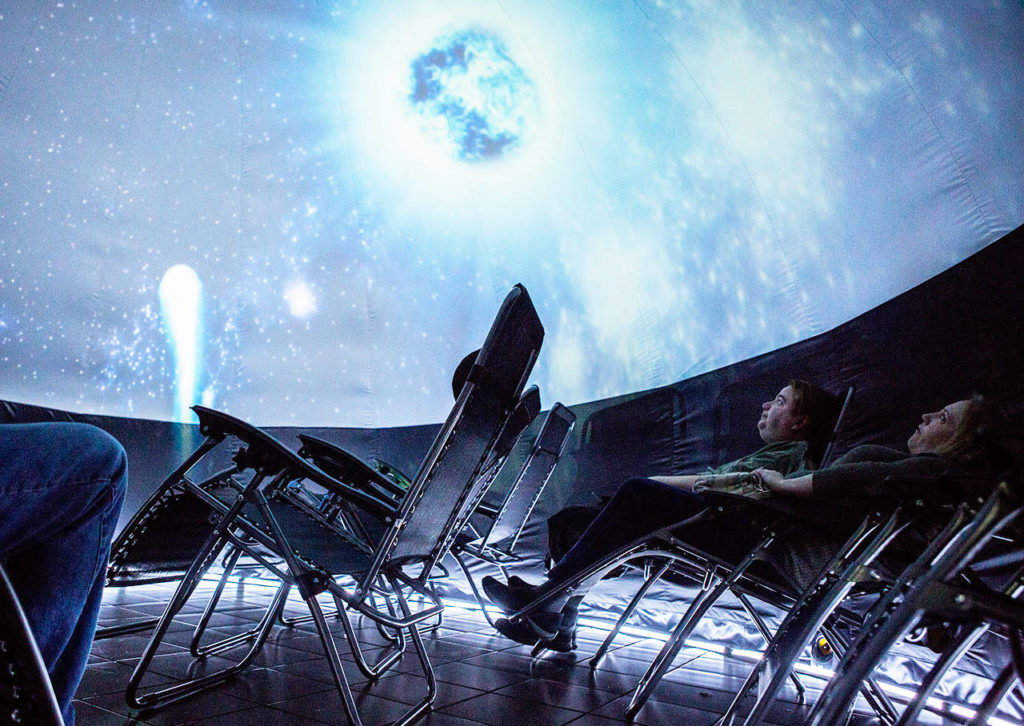 People look up at the projection inside the Planetarium 360 before the start of the show at the Everett Mall on Saturday. (Olivia Vanni / The Herald)

