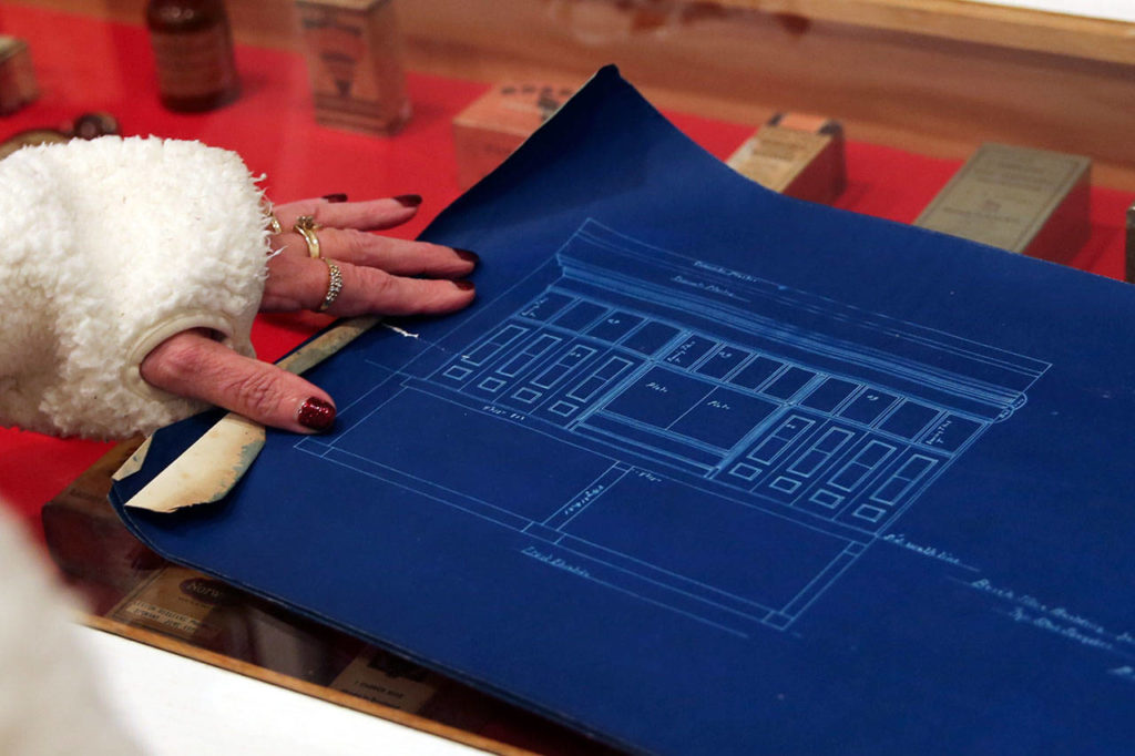 Donna Hurst, treasurer, spreads blueprints found in the safe at Marysville Historical Society. The safe was opened by a Japanese game show after 112 years. (Kevin Clark / The Herald)
