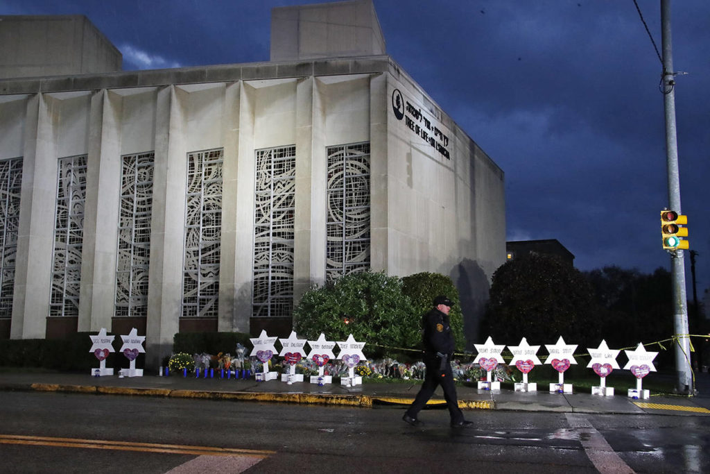 In this Oct. 28 photo, a Pittsburgh Police officer walks past the Tree of Life Synagogue and a memorial of flowers and stars in Pittsburgh in remembrance of those killed and injured when a shooter opened fire during services Saturday at the synagogue. (AP Photo/Gene J. Puskar, File)
