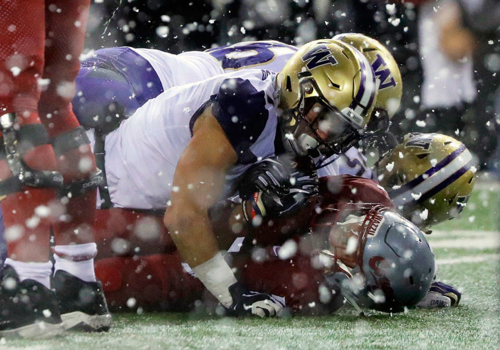 Washington State’s Travell Harris (lower right) is tackled by Washington safety Taylor Rapp (upper left) as snow flies during the first half of the Apple Cup on Nov. 23, 2018, in Pullman. (AP Photo/Ted S. Warren)
