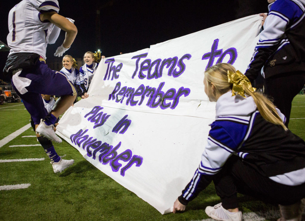 The Lake Stevens Cheer team holds a banner for the team as they run onto the field after halftime during the Class 4A state state semifinal game against Woodinville at Pop Keeney Stadium on Saturday, Nov. 24, 2018 in Bothell, Wa. (Olivia Vanni / The Herald)
