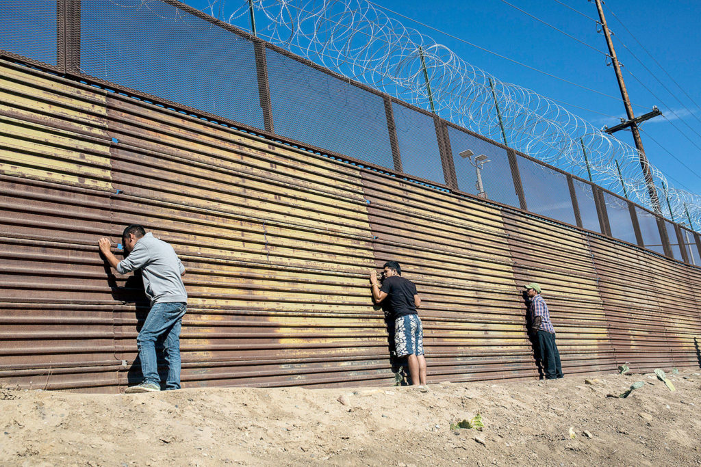 Migrants peer through the border wall after pushing past Mexican police at the Chaparral crossing in Tijuana, Mexico, on Sunday. (AP Photo/Rodrigo Abd)
