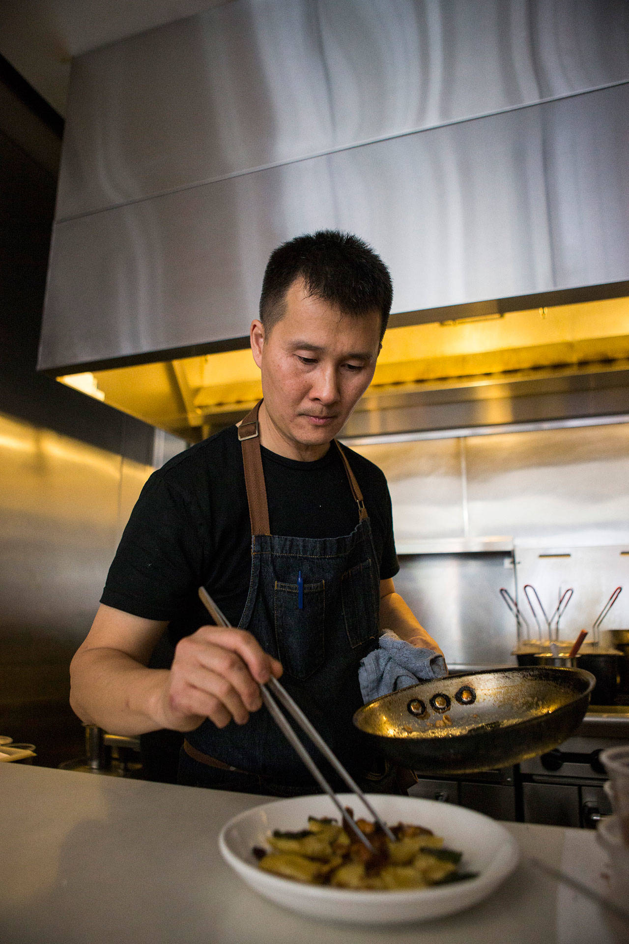 Capers + Olives chef and owner Jimmy Liang places sage leaves on agnolotti pasta in the kitchen of his Everett restaurant. (Olivia Vanni / The Herald)