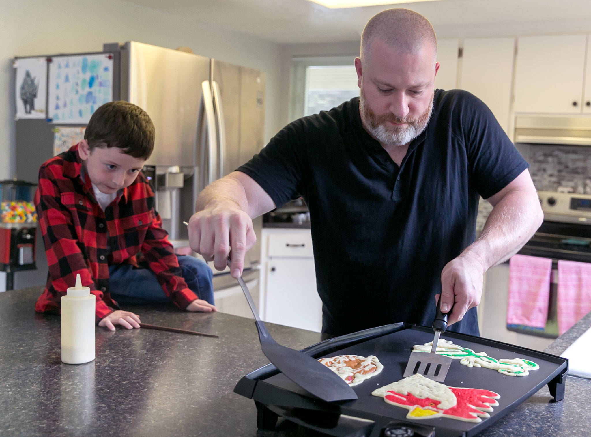 Pancake artist Brek Nebel makes pancakes under the watch of his son Koen, 7, at their home in Snohomish. (Kevin Clark / The Herald)