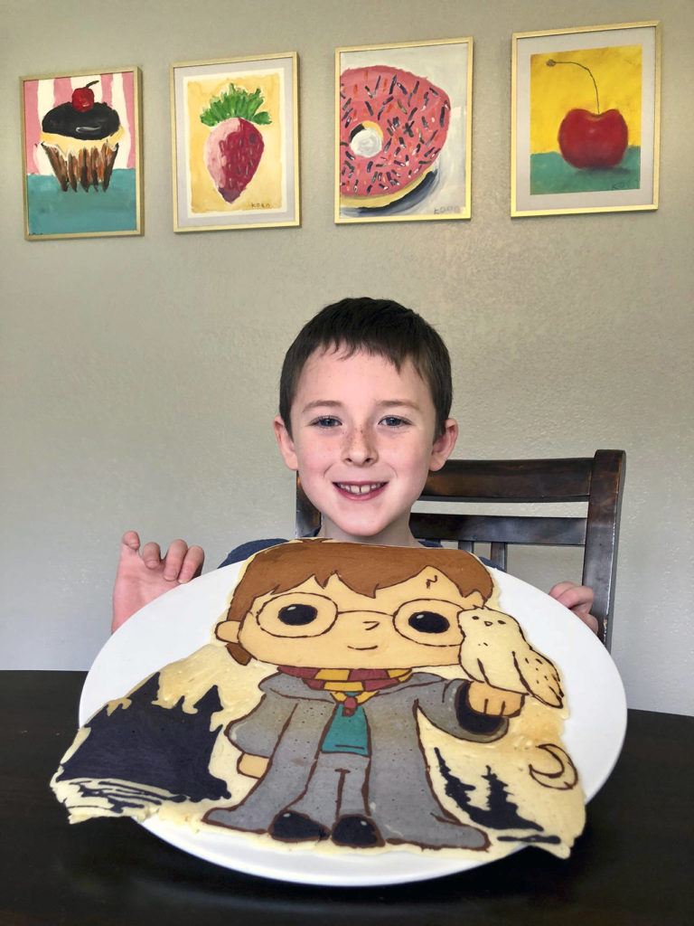 Koen Nebel, 7, holds a Harry Potter pancake he helped his father make — and later helped eat. The artwork on the wall was done by Koen. (Andrea Brown / The Herald)
