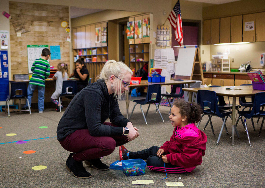 Emerson Elementary teacher Amanda Willoughby talks with Kaya while she works on one of her school activities Thursday in Everett. (Olivia Vanni / The Herald)
