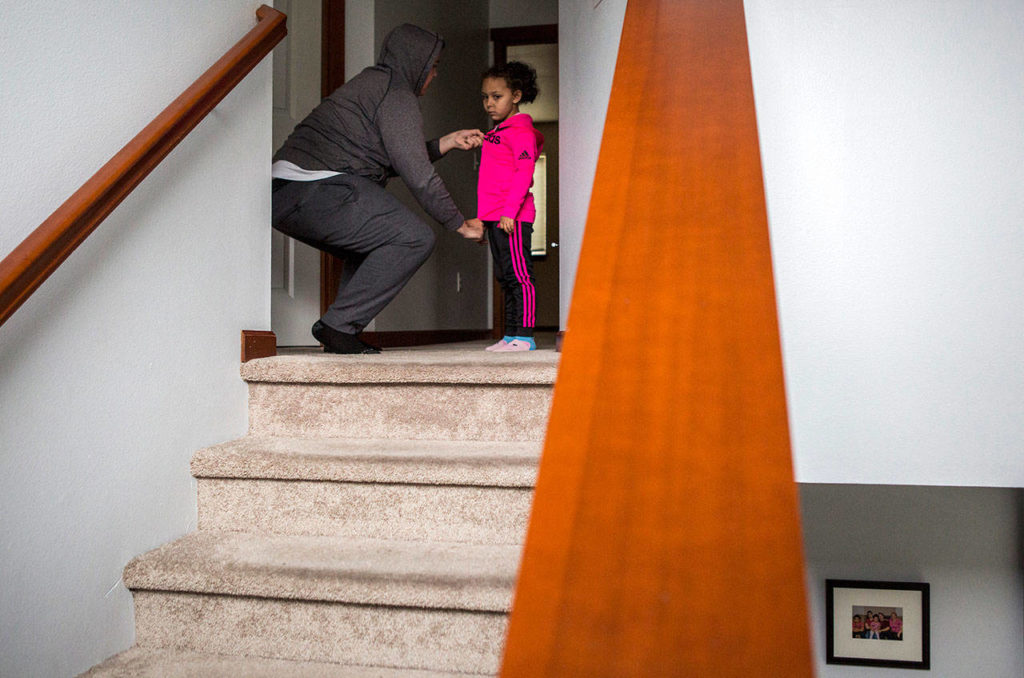 Kaya gets help zipping up her jacket as she gets ready for school Thursday in Everett. (Olivia Vanni / The Herald)
