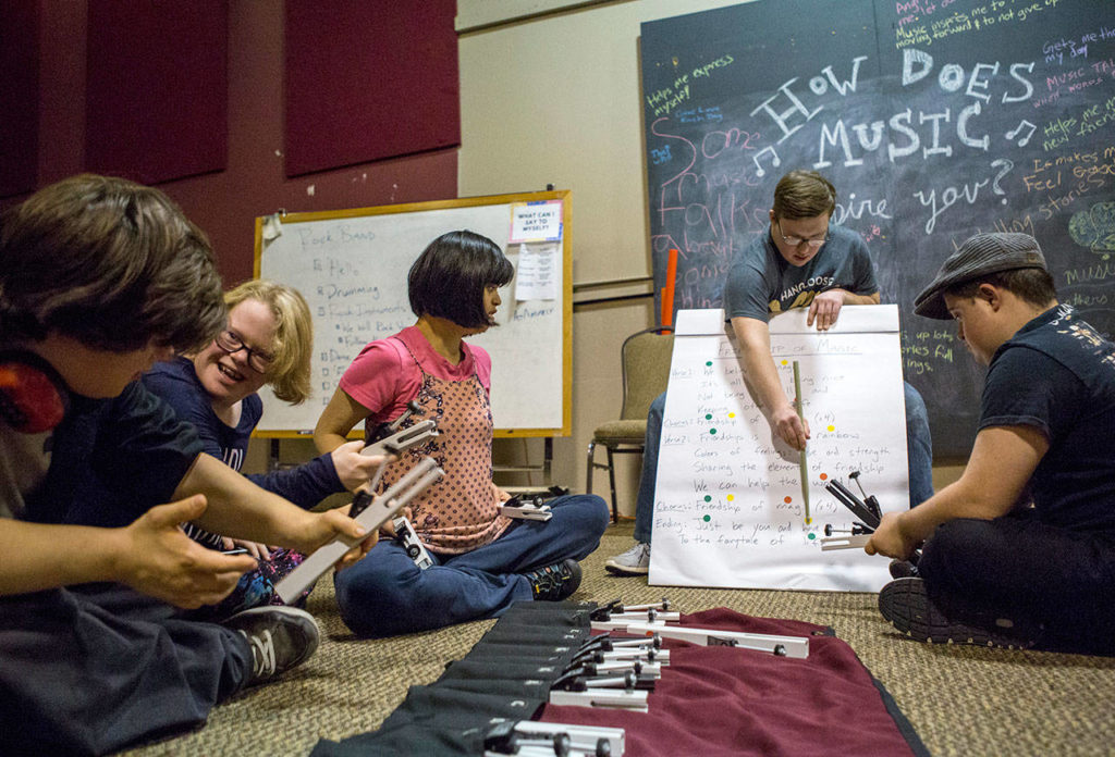 Drew Rogerson (center), 21, center, helps lead the group in a song they wrote last week during the Music YoU-ROCK program at the Northwest Music Hall in Everett. (Olivia Vanni / The Herald)
