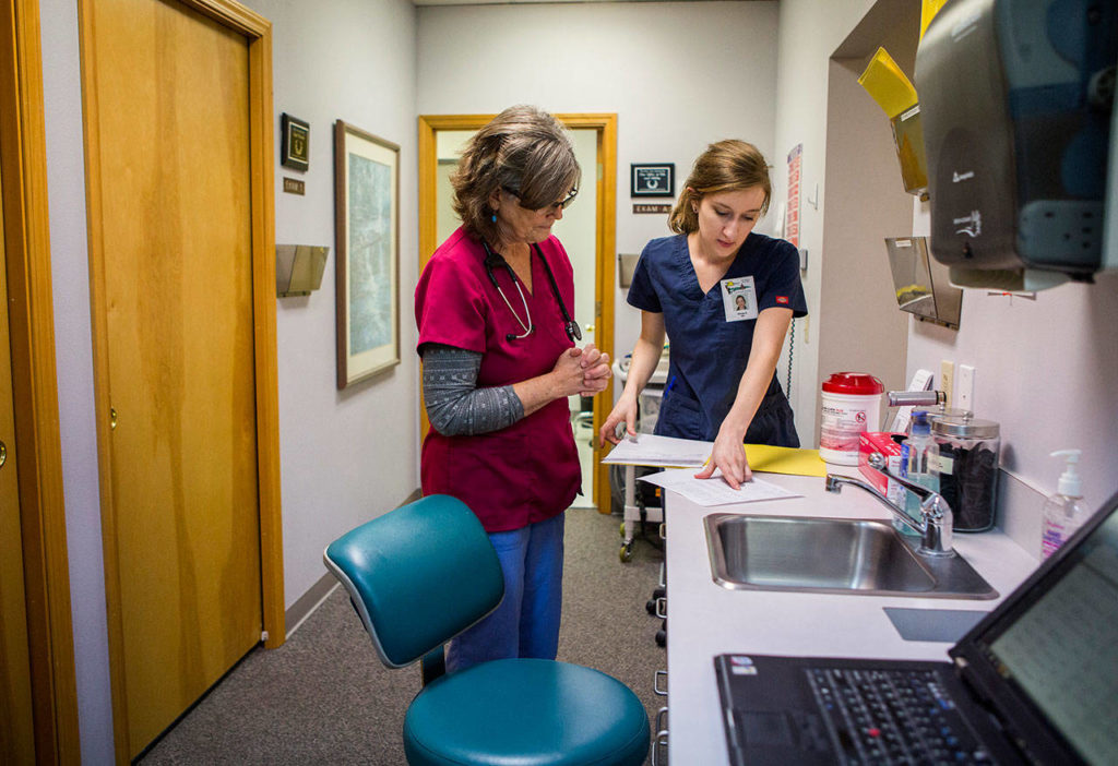 Susan Sanderson (left) and Clarisa Shook look to see what patient is next at the Safe Harbor Clinic in Stanwood. (Olivia Vanni / The Herald) 
