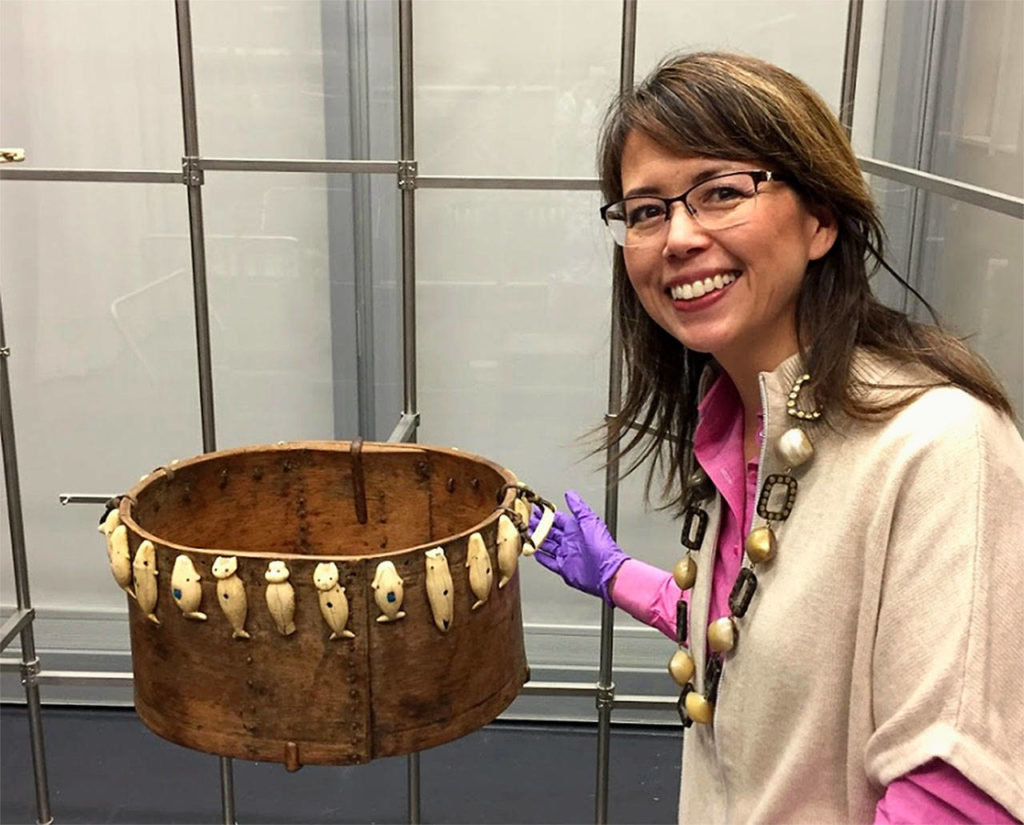 Everett artist Susan Ringstad Emery with an artifact from the Smithsonian collection at the Anchorage Museum. Items are tethered to movable metal racks to protect them from earthquake damage.
