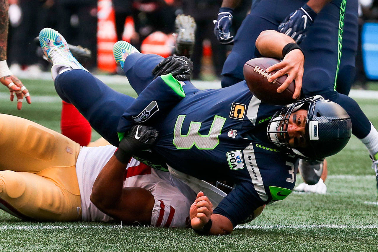 Seahawks quarterback Russell Wilson is tackled by former Seahawk Malcolm Smith during Sunday’s NFL game at CenturyLink Field. Wilson threw four touchdown passes in the game. (Kevin Clark/The Herald)