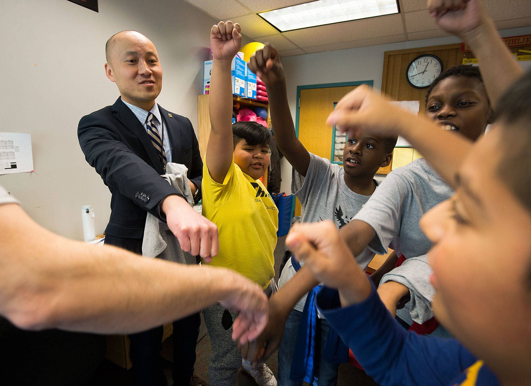 Horizon Elementary School Principal Edmund Wong bumps fists with students in the Wednesday Boys Club program at the end of the session Wednesday, Dec. 5, in Everett. (Andy Bronson / The Herald)