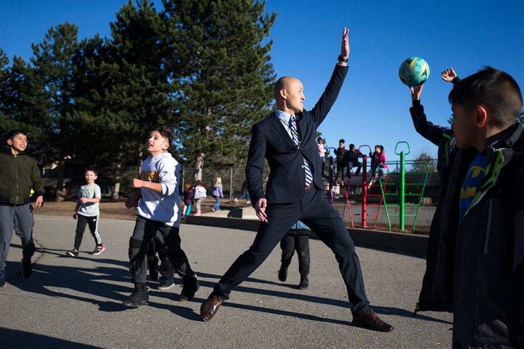 Horizon Elementary School Principal Edmund Wong puts up a hand as a student shoots for a basket during recess on Wednesday, Dec. 5, in Everett. (Andy Bronson / The Herald)
