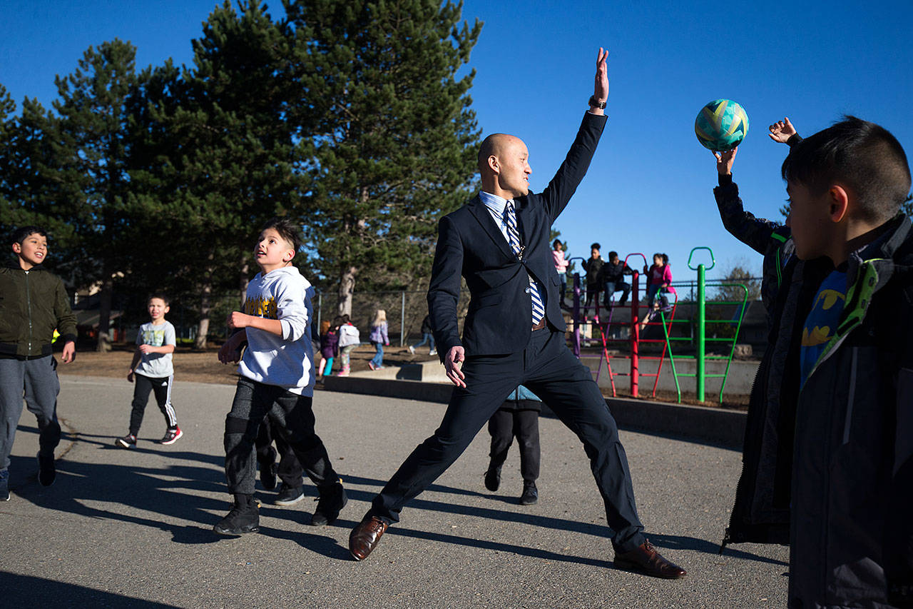 Horizon Elementary School Principal Edmund Wong puts up a hand as a student shoots for a basket during recess on Wednesday, Dec. 5, in Everett. (Andy Bronson / The Herald)