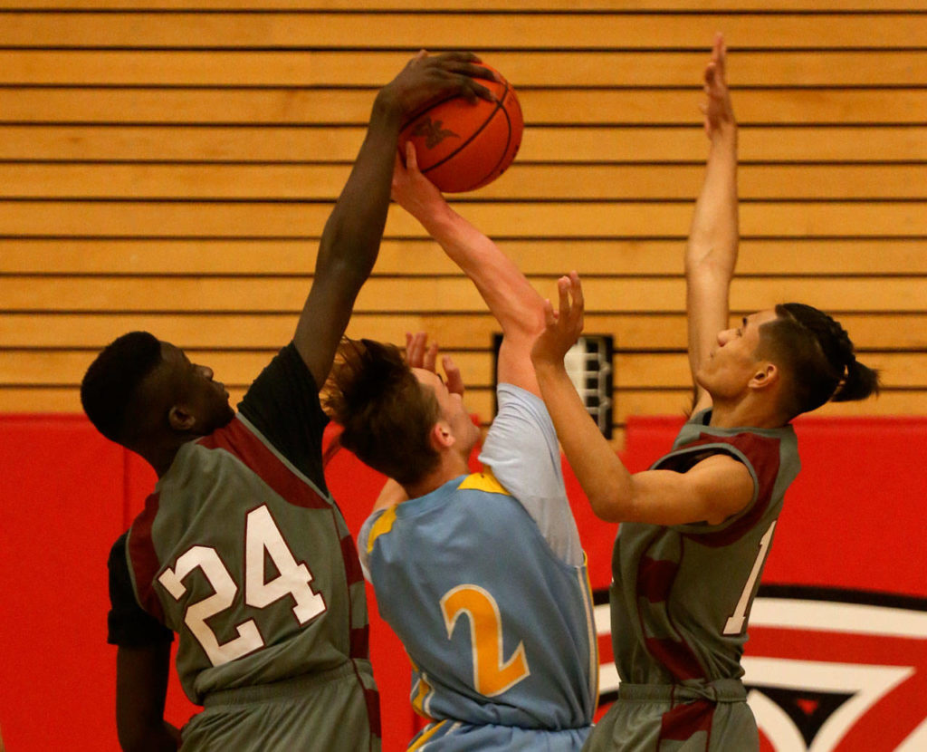 Cascade’s Baba Kolly (left) blocks Everett’s Taras Fesiienko’s shot as the Bruins’ Luke Wugumgeg defends during the annual BruGull Fest game between the cross-town rivals Friday at the Walt Price Student Fitness Center at Everett Community College. (Kevin Clark / The Herald)
