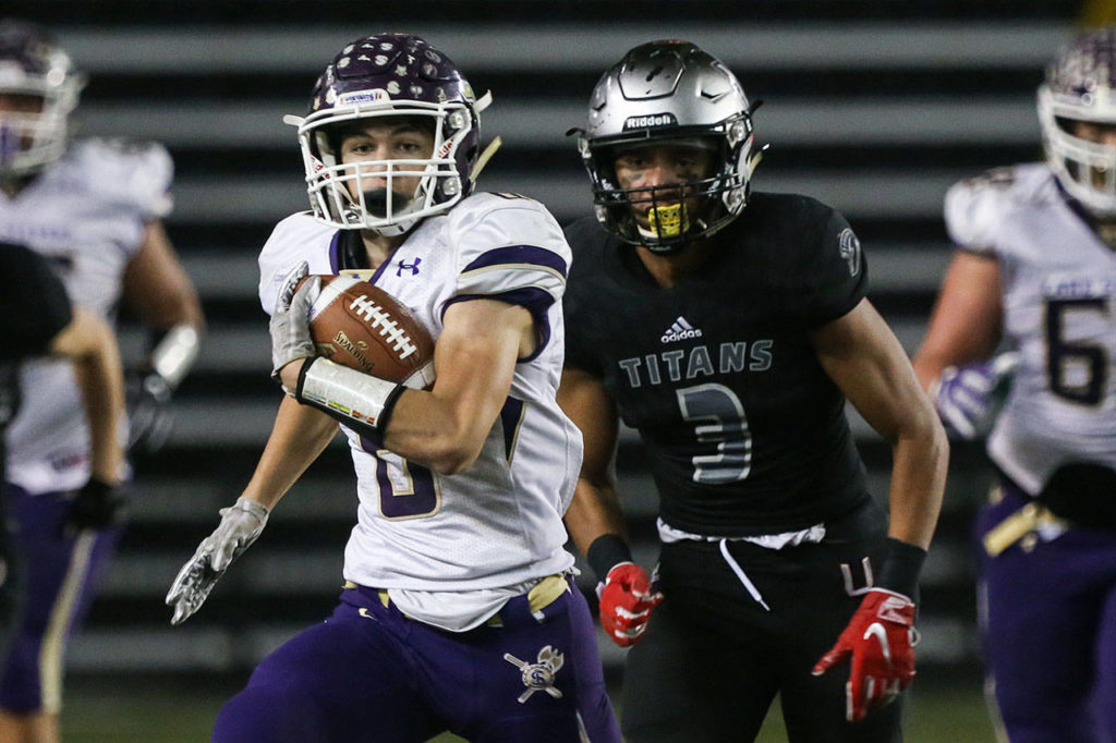 Lake Stevens’ Dallas Landeros runs the ball with Union’s Darien Chase trailing during the 4A state football championship game on Dec. 1, 2018, at the Tacoma Dome. (Kevin Clark / The Herald)
