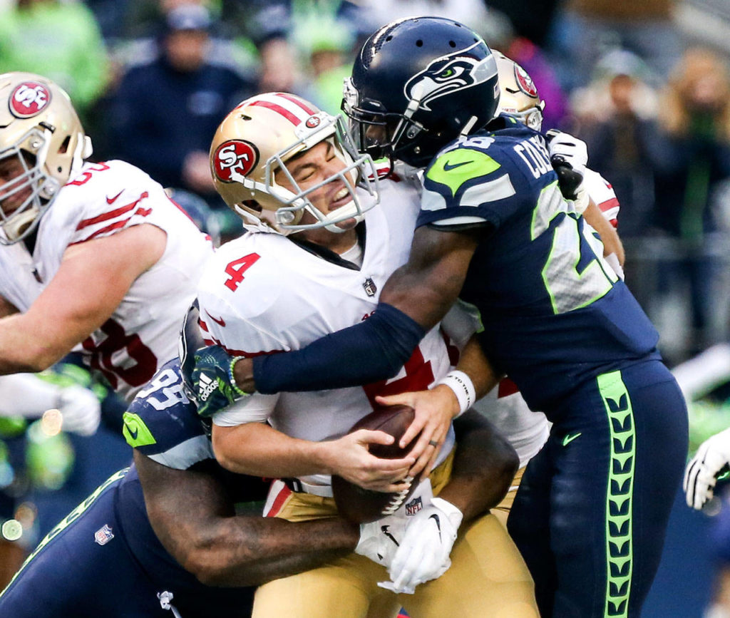 49ers quarterback Nick Mullens is sandwiched by Seahawks defensive lineman Quinton Jefferson (left) and Seahawks corner back Justin Coleman for a sack Sunday afternoon at CenturyLink Field in Seattle on December 2, 2018. Seahawks won 46-16. (Kevin Clark / The Herald)
