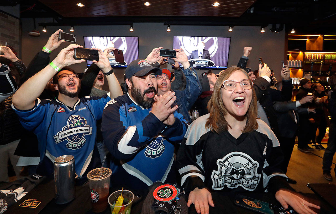 Ryan Kelly (left), Otto Rogers (center) and Rebecca Moloney cheer the announcement of a new NHL hockey team in Seattle at a celebratory party on Dec. 4, 2018, in Seattle. (AP Photo/Elaine Thompson)