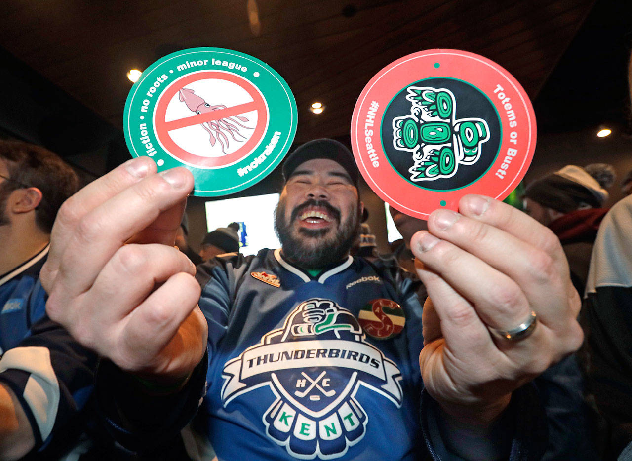 Otto Rogers playfully holds up a sticker against the proposed name “Kraken” and one in support of “Totems” following the announcement that NHL expansion team has been awarded to Seattle. (AP Photo/Elaine Thompson)