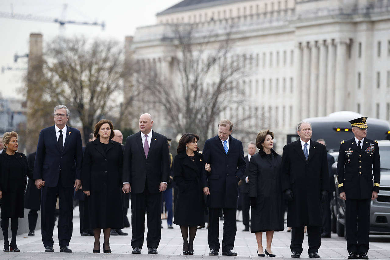 From right, former President George W. Bush, former first lady Laura Bush, Neil Bush, Sharon Bush, Bobby Koch, Doro Koch, Jeb Bush and Columba Bush, stand just prior to the flag-draped casket of former President George H.W. Bush being carried by a joint services military honor guard from the U.S. Capitol on Wednesday in Washington. (AP Photo/Alex Brandon, Pool)