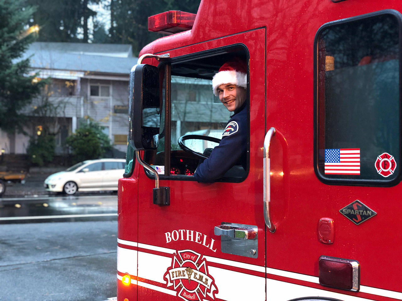 Firefighter Tyler Griffith sits in the driver’s seat wearing a Santa cap. Local firefighters will be decorating a fire engine this year as they drive around gathering donations and meeting with residents. (City of Bothell)