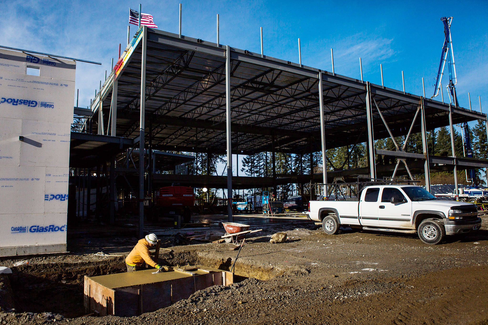 A worker smooths out freshly poured concrete in front of what will be the gym of the Tambark Creek Elementary School on Friday in Bothell. (Olivia Vanni / The Herald)