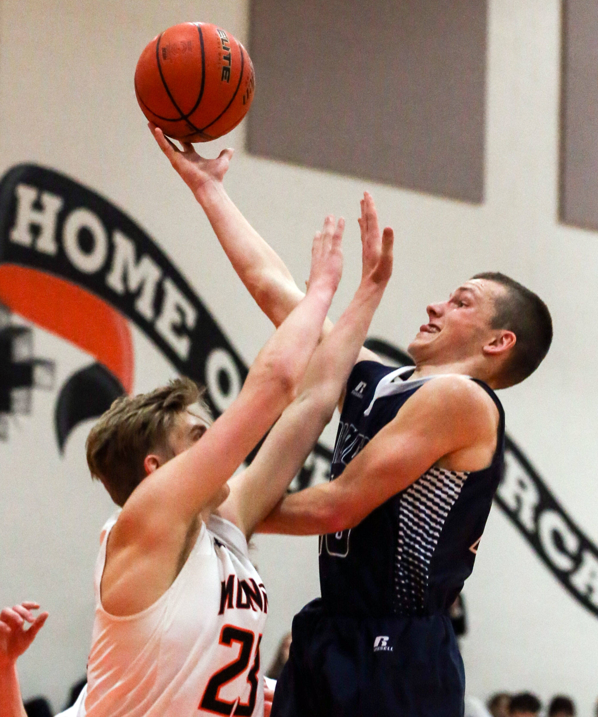 Arlington’s Anthony Whitis (left) and attempts a shot over Monroe’s Sam Olson on Friday night. Arlington won 62-54. (Kevin Clark / The Herald)