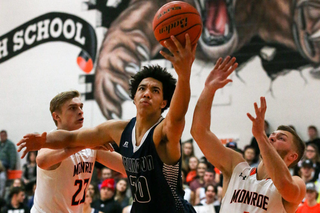 Arlington’s Will Abram (center) outreaches Monroe’s Sam Olson (left) and Efton Chism (right) for a rebound on Friday night at Monroe High Schoo. Arlington won 62-54. (Kevin Clark / The Herald)
