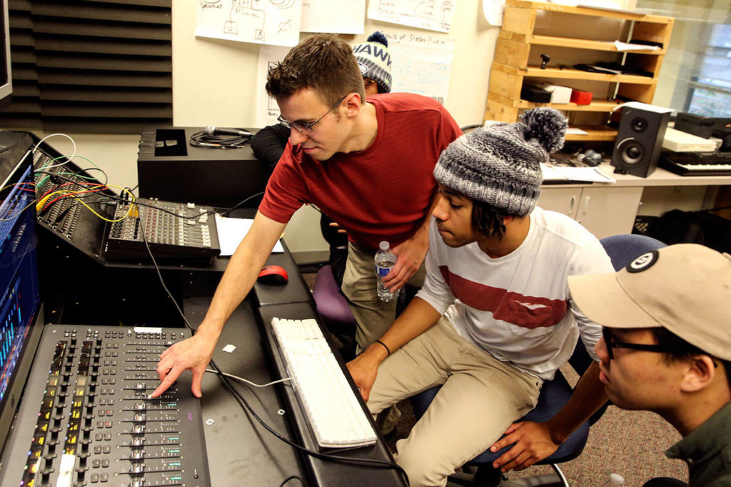 Edmonds Community College music and audio production instructor Nick Sibicky makes an adjustment on the sound board as students Isaac Kone (center) and Steven Ly watch. (Kevin Clark / The Herald)
