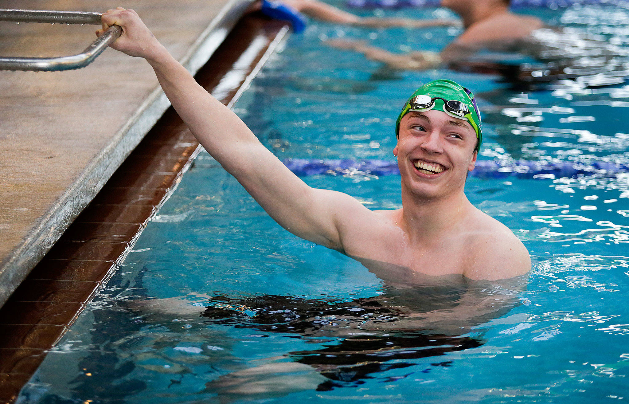 Edmonds-Woodway senior Daniel Eno smiles at teammates after winning his race at the Lynwood Pool on Tuesday, Dec. 18, 2018 in Lynnwood, Wa. Eno has qualified for the 3A state meet in each of the last two seasons and hopes to qualify in multiple events for this season’s state meet. He’s also a world traveler, can speak multiple languages and is accomplished student (he’s a member of Edmonds-Woodway’s International Baccalaureate program).(Andy Bronson / The Herald)                                Edmonds-Woodway senior Daniel Eno smiles at teammates after winning his race at the Lynnwood Pool on Dec. 18. (Andy Bronson / The Herald)