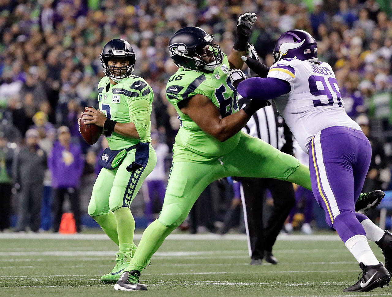 Seahawks quarterback Russell Wilson (left) looks for room to pass as Jordan Simmons (66) blocks the Vikings’ Linval Joseph in the first half of a game on Dec. 10, 2018, in Seattle. (AP Photo/Ted S. Warren)