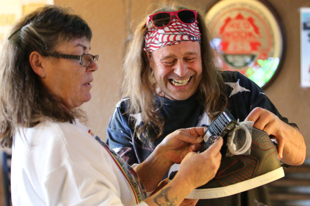 Teri Banks (left) looks at a pair of sneakers with bluetooth speakers in the soles as Wade Tucker laughs on Saturday, Dec. 15, at Twin Foxes in Everett. (Kevin Clark / The Herald)
