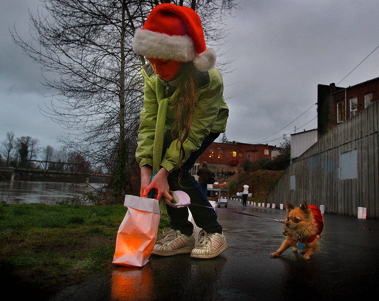 In this 2009 photo, Christina Deierling, of Snohomish, lights candles along the Riverfront Trail in old Snohomish, despite objections from her little dog, Bella, who appeared quite nervous about the flame in the bag. When the lighting was finished, people took a candlelight walk to celebrate the winter solstice. (Dan Bates / The Herald)