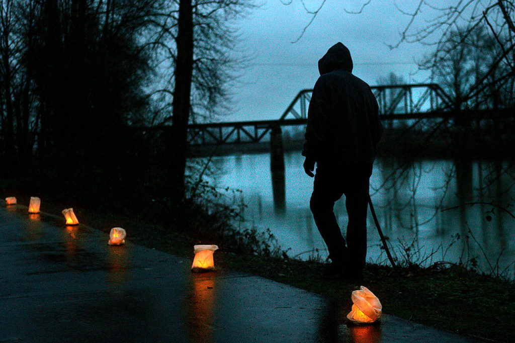 Steve Erie uses a walking stick as he makes his way eastward alongside candles on the Snohomish River Trail between Cady Park and Avenue D in Snohomish, just two minutes before the winter solstice in 2006. (Dan Bates / The Herald)
