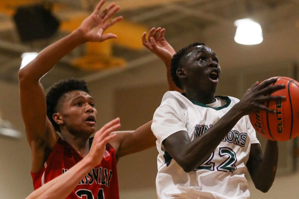 Edmonds-Woodway’s Mutdung Bol goes up to the basket with Marysville Pilchuck’s RaeQuan Battle trailing during Friday’s Wesco 3A game in Edmonds. Battle’s buzzer-beating layup gave the Tomahawks a 55-53 win over Bol and the Warriors. (Kevin Clark / The Herald)
