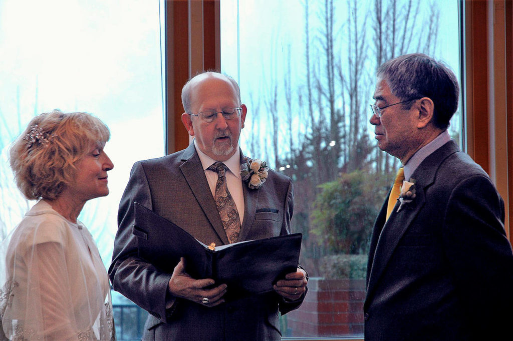 In the spacious west end of the Everett Public Library overlooking Port Gardner, officiant David Cooper performs the wedding uniting Gaylen Blue and Ed Wada. (Everett Public Library)
