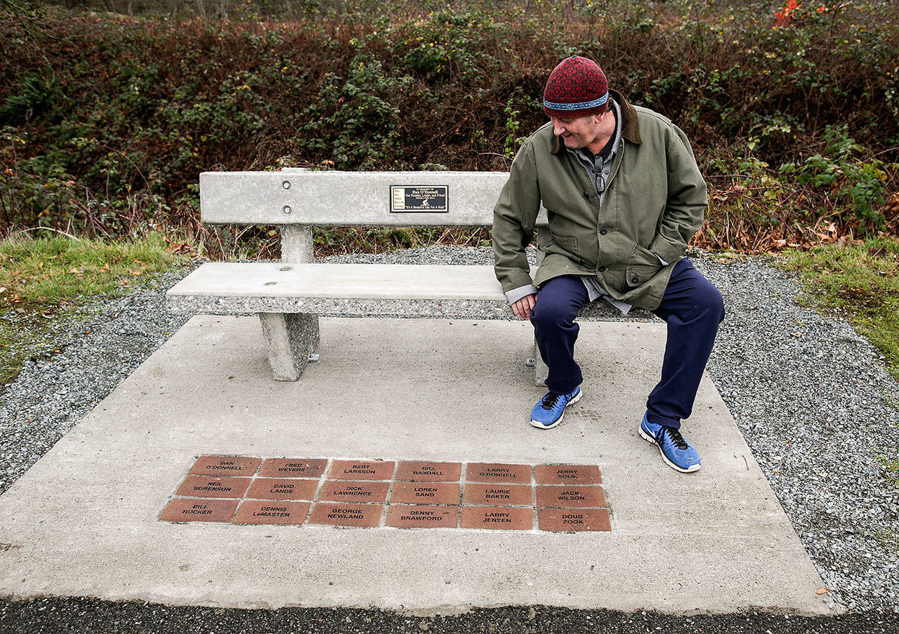 Steve O’Donnell looks over a concrete bench in honor of his father Dan along the Centennial Trail on Wednesday, Dec. 19, in Arlington. Dan was the founder of “The Big Shots Bicycle Group,” whose member’s names are inscribed in bricks at the base of the bench. (Andy Bronson / The Herald)
