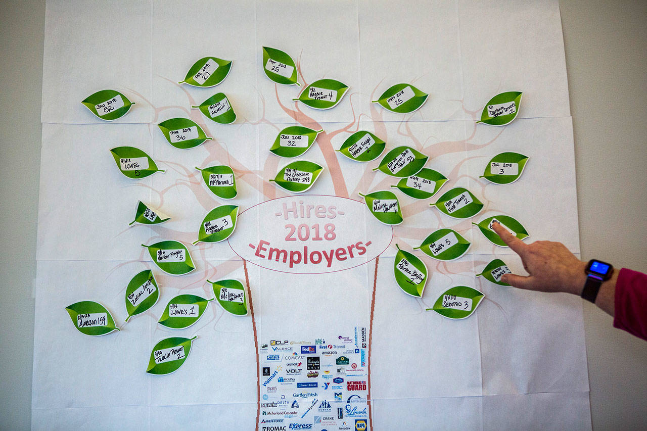 Brenda Banks points out some of the recent hires on a “hires tree” at the WorkSource office in Everett Station on Dec. 7. (Olivia Vanni / The Herald)