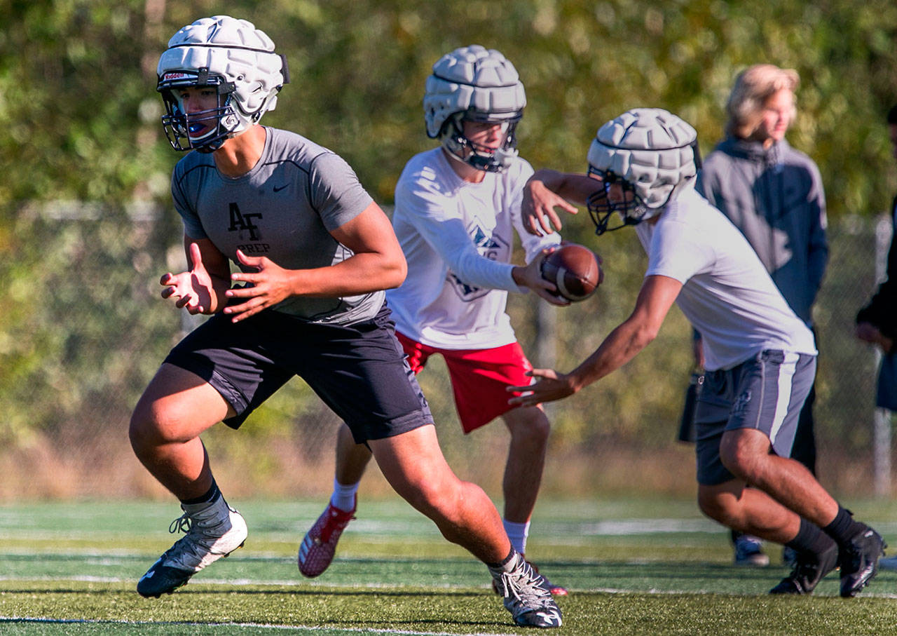 Glacier Peak’s Ma’ake Fifita (left) blocks with quarterback Ayden Ziomas handing off to Corbin Ferrie during a practice on Oct. 4, 2018, at Glacier Peak High School in Snohomish. (Kevin Clark / The Herald)