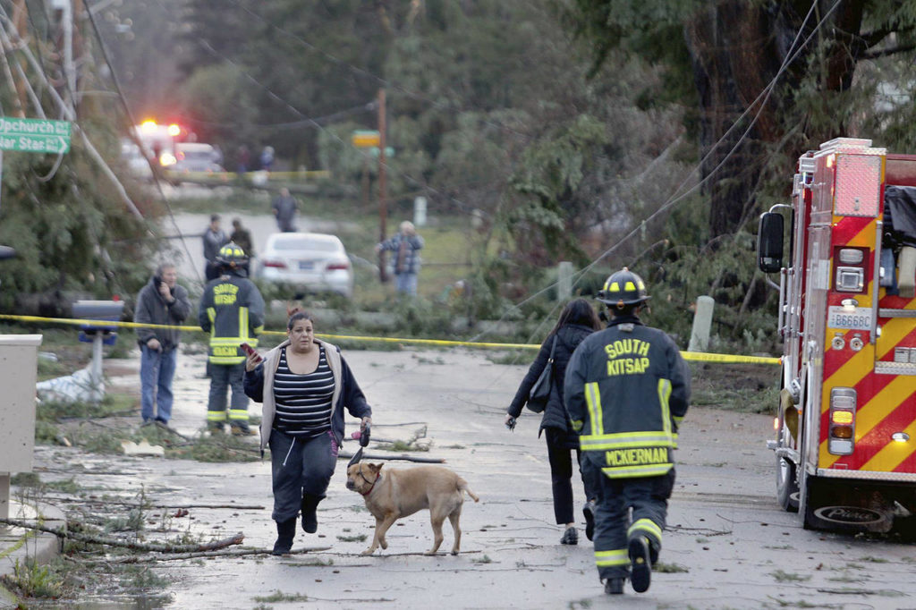 Residents run away and emergency personnel run toward the damage on Harris Road in Port Orchard on Tuesday, after a tornado touched down. (Larry Steagall/Kitsap Sun via AP)
