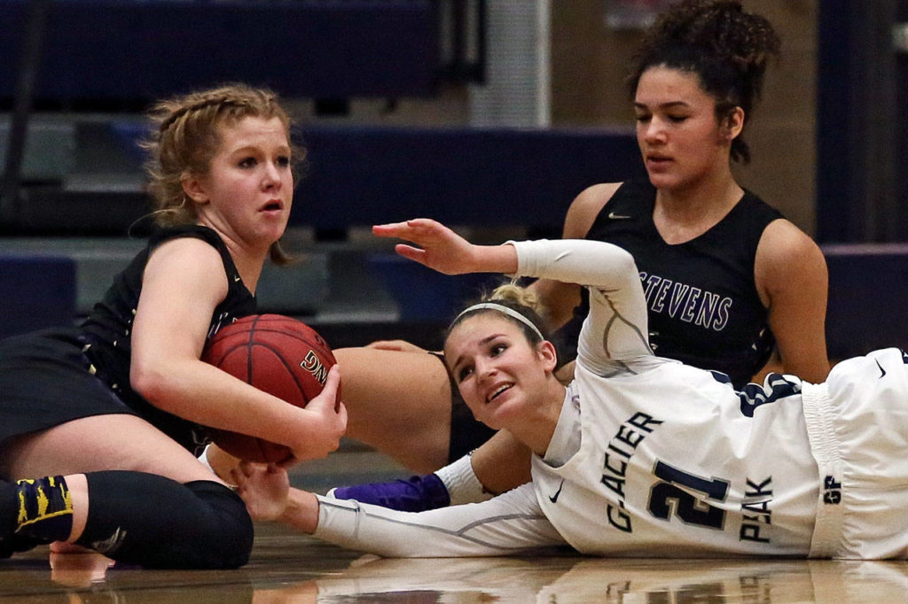 Lake Stevens’ Cori Wilcox gathers a loose ball with Glacier Peak’s Sydney Guffey (right bottom) and Lake Stevens’ Baylor Thomas looking on Tuesday night at Glacier Peak High School in Snohomish on December 18, 2019. Glacier Peak won 68-50. (Kevin Clark / The Herald)
