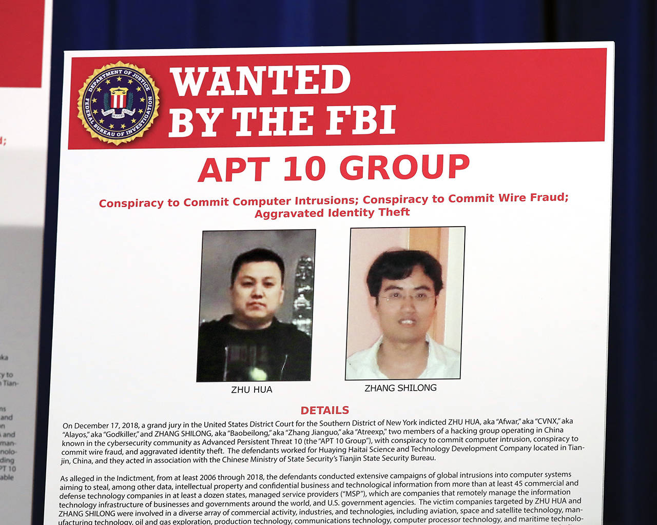 A poster displayed during a news conference at the Department of Justice in Washington on Thursday shows two Chinese citizens suspected to be with the group carrying out an extensive hacking campaign to steal data from U.S. companies. (AP Photo/Manuel Balce Ceneta)
