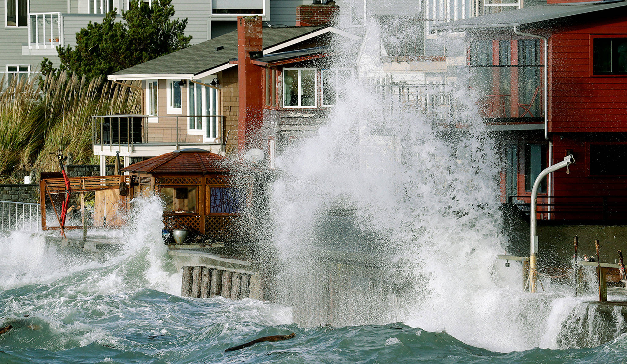 Waves crash against a seawall next to homes at high tide during a windstorm Thursday in Seattle. (AP Photo/Elaine Thompson)