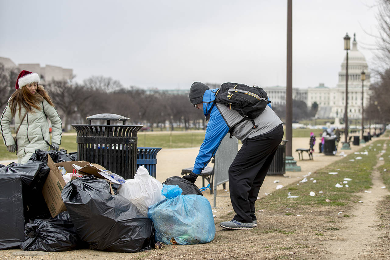 The Capitol building is visible as a man who declined to give his name picks up garbage and stacks it near a trash can during a partial government shutdown on the National Mall in Washington on Tuesday. (AP Photo/Andrew Harnik)