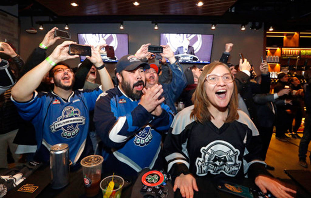 In this Dec. 4, 2018 photo, Ryan Kelly (left) Otto Rogers and Rebecca Moloney cheer the announcement of a new NHL hockey team in Seattle at a celebratory party in Seattle. (AP Photo/Elaine Thompson, File)
