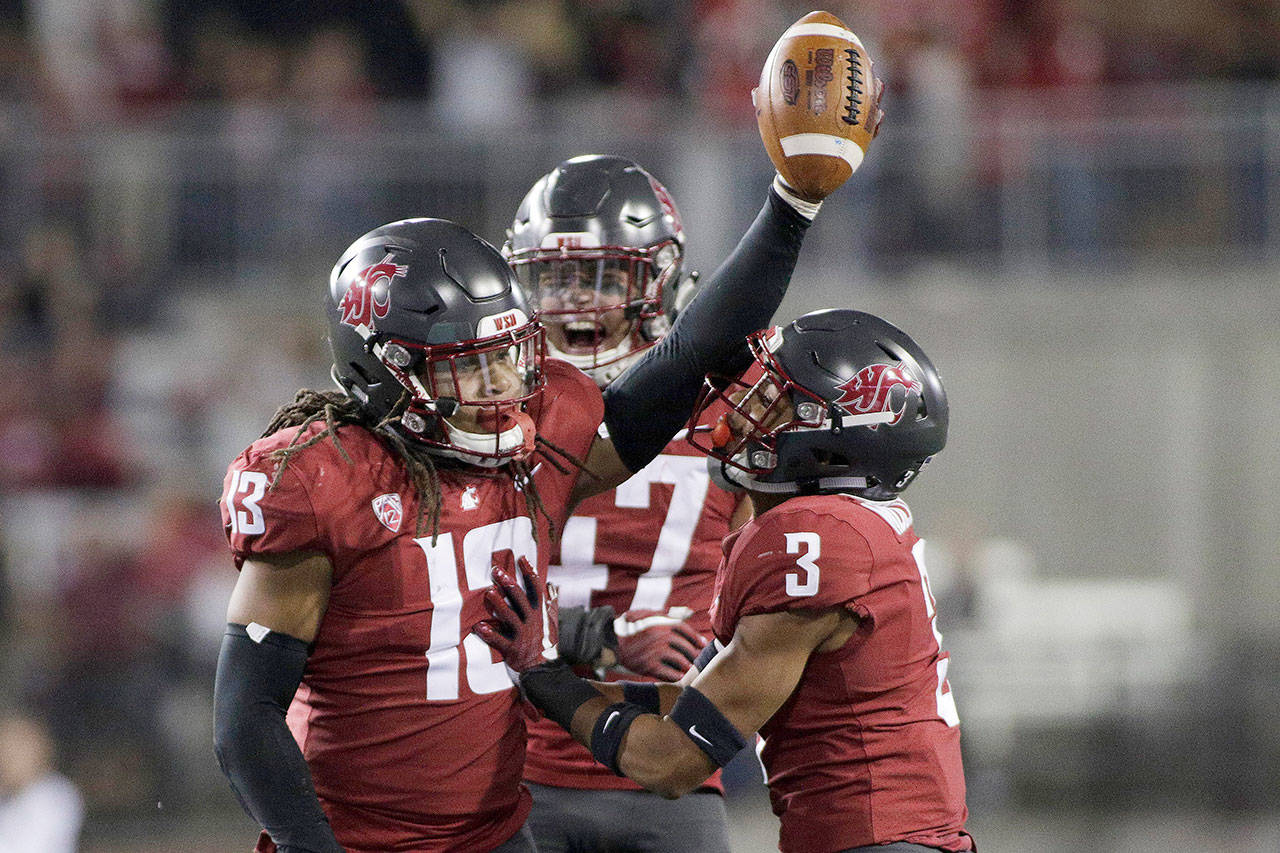 Washington State’s Jahad Woods (13) celebrates with Darrien Molton (3) and Peyton Pelluer (47) after Woods’ interception during a Sept. 15 game against Eastern Washington in Pullman. (AP Photo/Young Kwak)